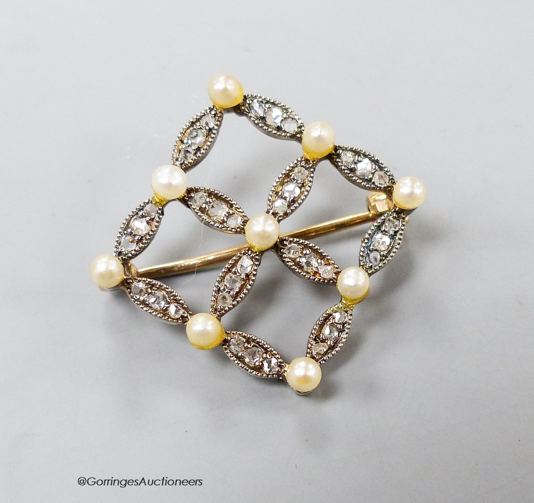 An Edwardian yellow metal, seed pearl and diamond set openwork square brooch, 19mm, gross 3.2 grams.